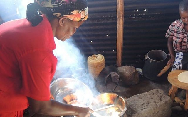 Ruth Wangechi cooks mandazi, a fried dough popular for breakfast, over the fire. Since there is no oven, she also deep-fries challah the same way. (Melanie Lidman/Times of Israel)