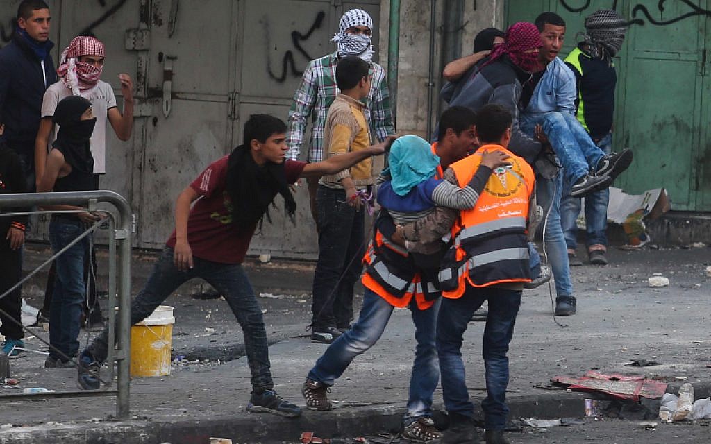 Palestinians carry a man wounded in clashes with Israeli soldiers in the West Bank city of Hebron, October 31, 2015. (Flash90)