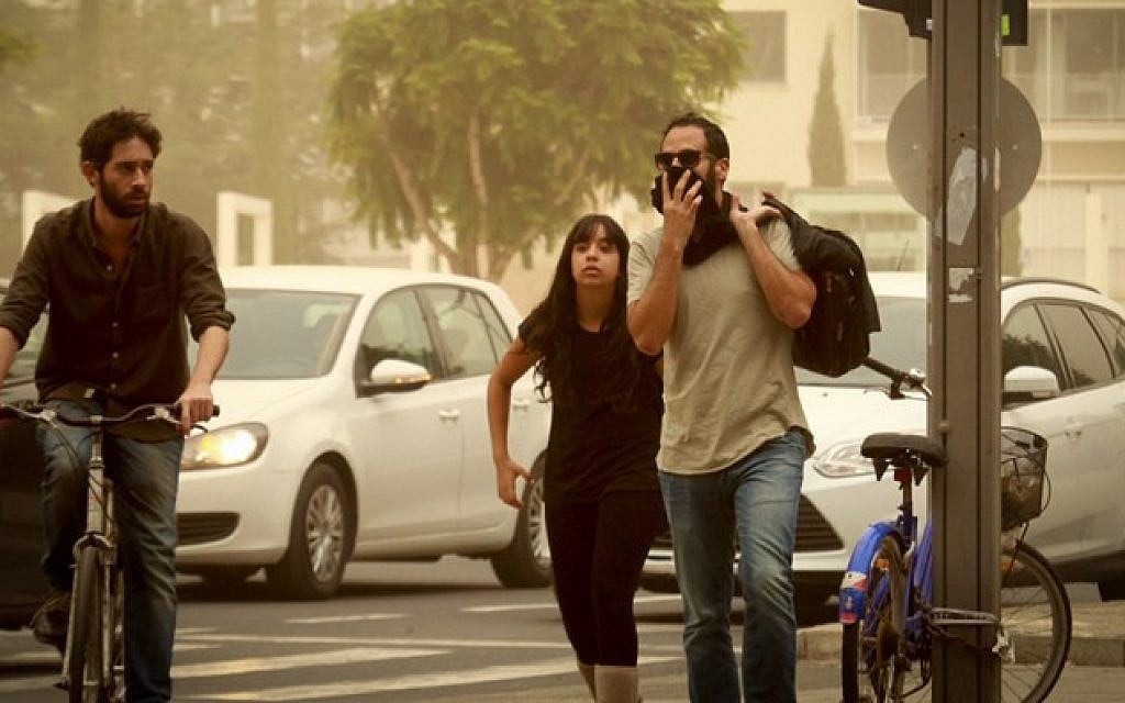 A man covers his face while crossing the street as a sand storm hits Israel on November 04, 2015. (Flash90)