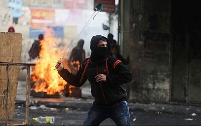 Palestinian protesters use slingshots to hurl stones towards Israeli troops during clashes in the West Bank city of Hebron, November 5, 2015. (by Flash90)