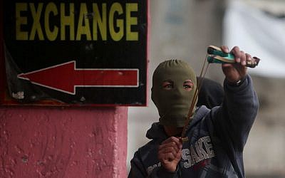 A Palestinian use a slingshot to hurl stones towards Israeli troops during clashes in the West Bank city of Hebron, November 5, 2015. (Flash90)