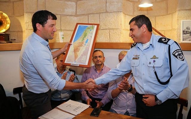 West Bank settlement council CEO Sheila Adler, left, shakes hands with Deputy Commissioner Shlomi Michael, right, police commander of the Judea and Samaria District during a meeting security situation, in the West Bank, November 9, 2015. (Gershon Elinson/Flash90
