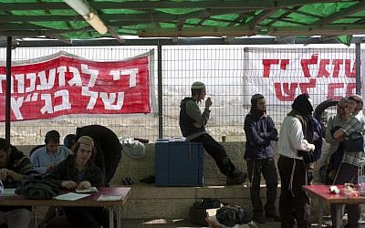 Right wing activists seen at the Ayelet Hashahar synagogue in the West Bank settlement of Givat Ze'ev, sit in front of signs reading "Stop the discrimination of the High Court," on November 16, 2015. (Lior Mizrahi/Flash90)