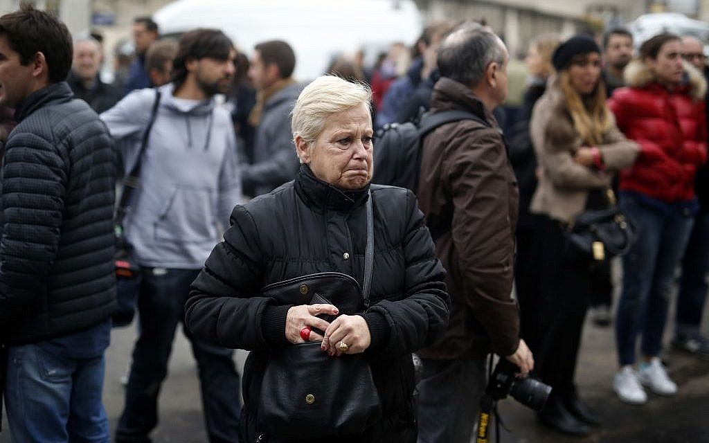 People react in front of the Carillon cafe and the Petit Cambodge restaurant in Paris Saturday Nov. 14, 2015, a day after over 120 people were killed in a series of shootings and explosions. (AP Photo/Jerome Delay)