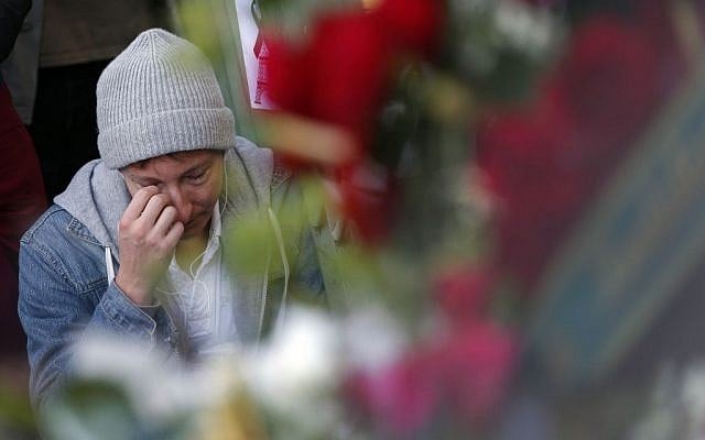 A mourner wipes his eye outside the Bataclan concert hall in Paris, Sunday, Nov. 15, 2015. (AP Photo/Christoph Ena)