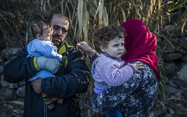 A man and a woman hold their children after arriving on a dinghy from a Turkish coast to the northeastern Greek island of Lesbos, Saturday, Nov. 14, 2015. (AP Photo/Santi Palacios)