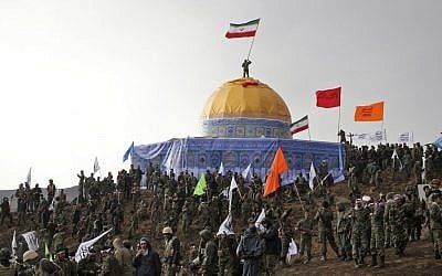In this Friday, Nov. 20, 2015 photo released by the Tasnim News Agency, members of the Basij, the paramilitary unit of Iran's Revolutionary Guard, gather around a replica of Jerusalem's gold-topped Dome of the Rock mosque as one of them waves an Iranian flag from atop the dome during a military exercise. (AP Photo/Tasnim News Agency, Mahmoud Hosseini)