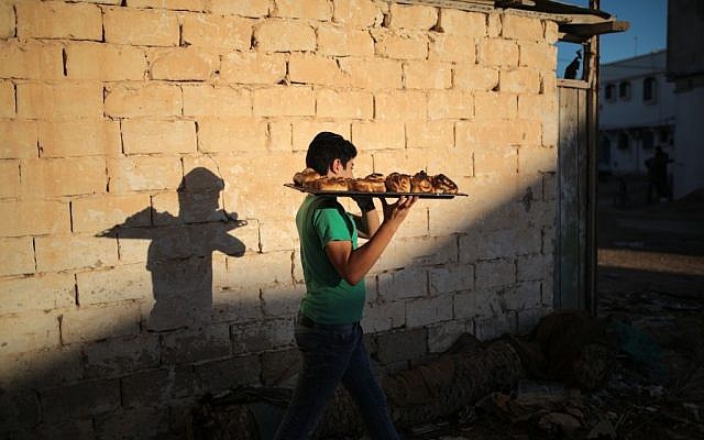 A boy heads home with freshly baked Challah, a special Jewish bread, at the beginning of Shabbath, at Hara Kbira, the main Jewish neighborhood on the Island of Djerba, southern Tunisia, October 29, 2015. (Photo by AP Photo/Mosa'ab Elshamy)