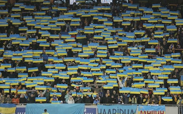 Spectators hold Ukrainian national flags during a minute silence for the victims of the Paris attacks before the Euro 2016 play-off first leg soccer match between Ukraine and Slovenia, in Lviv, Ukraine, Saturday, Nov. 14, 2015. (AP Photo/Efrem Lukatsky)