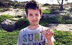 Itai Halperin, 8, and the head of an Iron Age statuette he found while walking near Tel Beit Shemesh. (Arik Halperin, courtesy of Israel Antiquities Authority)
