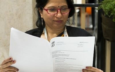 A summit attendee reads a copy of 'The adoption of the Paris agreement' at the COP21 Climate Conference in Le Bourget, on December 12, 2015. (AFP / MIGUEL MEDINA)