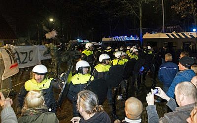 Police forces stand in front of protesters during a demonstration on December 16, 2015 at a council meeting about plans to open a refugee center for 1,500 refugees in Geldermalsen. (AFP/ANP/Jeroen Jumelet) 