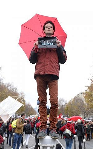 An activist holds up a sign reading in French 'I am climate' during a demonstration near the Arc de Triomphe in Paris on December 12, 2015, as a proposed accord is presented at the UN conference on climate change in Le Bourget. (AFP PHOTO/ALAIN JOCARD)