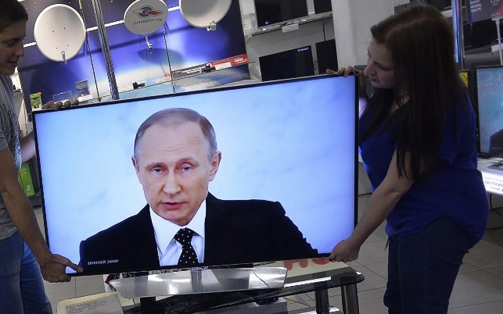 Shop assistants install a TV set at a shop in Moscow on December 3, 2015 during the broadcast of Russian President Vladimir Putin's annual state of the nation address. (AFP/Natalia Kolesnikova)