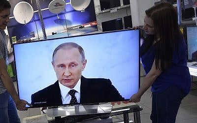 Shop assistants install a TV set at a shop in Moscow on December 3, 2015 during the broadcast of Russian President Vladimir Putin's annual state of the nation address. (AFP/Natalia Kolesnikova)