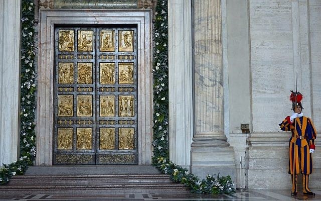 A Swiss guard stands by the "Holy Door" before it was opened by Pope Francis to mark the start of the Jubilee Year of Mercy, at St Peter's square in the Vatican, December 8, 2015. (AFP/VINCENZO PINTO)