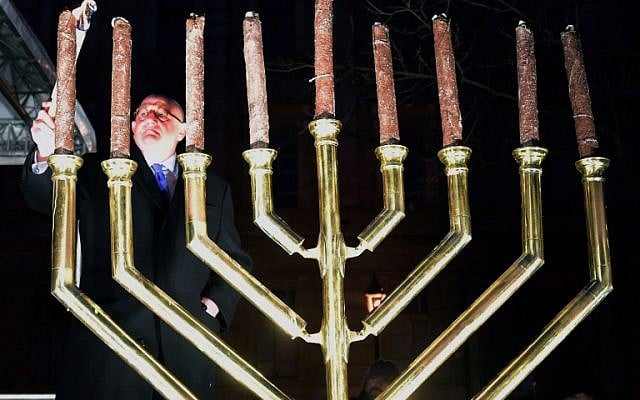Ira Forman (L), Special Envoy of the US government to Monitor and Combat Antisemitism lights a torch on the last day of Hanukkah in Szekesfehervar on December 13, 2015, during a joint commemoration for Hanukkah and a silent demonstration to protest against plans for a statue in honor of anti-Semitic Holocaust-era lawmaker Balint Homan. (AFP PHOTO/ATTILA KISBENEDEK)