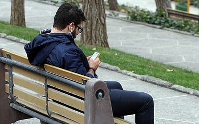 An Iranian man uses a smartphone at a park in Tehran on December 1, 2015. (AFP PHOTO / ATTA KENARE / AFP / ATTA KENARE)