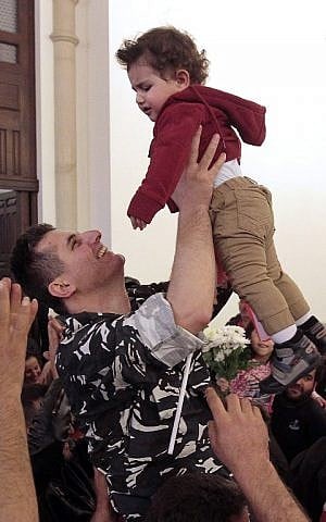 A member of Lebanons security forces, who was kidnapped by jihadist groups in early August 2014 in the eastern border town of Arsal, holds up a child during a ceremony at the government's palace in downtown Beirut on December 1, 2015. (AFP PHOTO /STR / AFP / STR)