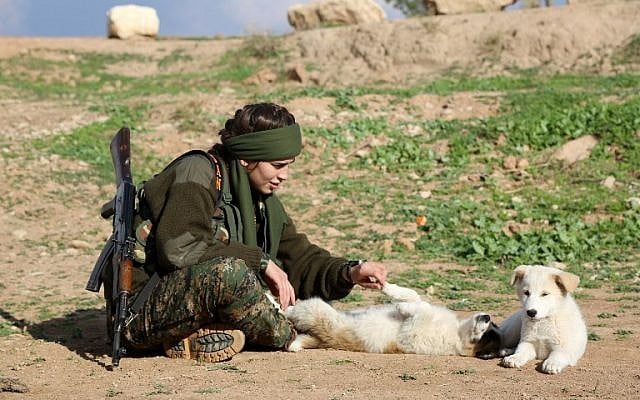 Syriac Christian Lucia, member of the battalion called the "Female Protection Forces of the Land Between the Two Rivers" fighting the Islamic State group, plays with a dog during a training on December 1, 2015 at their camp in the town of al-Qahtaniyah, near the Syrian-Turkish border (aka Kabre Hyore in Syriac, and Tirbespi in Kurdish).(AFP PHOTO / DELIL SOULEIMAN / AFP / DELIL SOULEIMAN0)