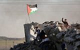 File: A Palestinian protester holds a national flag during clashes with Israeli security forces along the border with Israel in the eastern suburbs of Gaza City on December 4, 2015.(AFP PHOTO/MAHMUD HAMS)