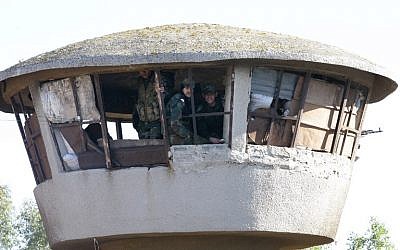 Members of the Syrian government forces sit in a tower at a military base as hundreds of civilians and Syrian rebel forces began evacuating the last opposition-held district of Waer in the central city of Homs, under a deal with the Syrian regime, December 9, 2015. (Photo by AFP Photo/Louai Beshara)