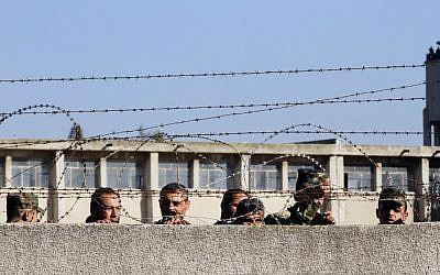 Members of the Syrian government forces look on as hundreds of civilians and Syrian rebel forces begin evacuating the last opposition-held district of Waer in the central city of Homs, under a deal with the Syrian regime, December 9, 2015. (AFP/Louai Beshara)