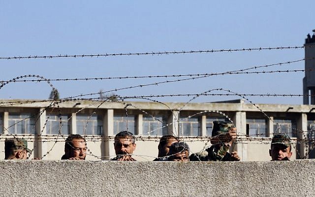 Members of the Syrian government forces look on as hundreds of civilians and Syrian rebel forces begin evacuating the last opposition-held district of Waer in the central city of Homs, under a deal with the Syrian regime, December 9, 2015. (AFP/Louai Beshara)
