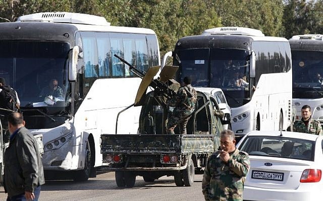 Members of the Syrian government forces escort buses carrying Syrians as hundreds of civilians and Syrian rebel forces began evacuating the last opposition-held district of Waer in the central city of Homs, under a deal with the Syrian regime, December 9, 2015. (Photo by AFP Photo/Louai Beshara)
