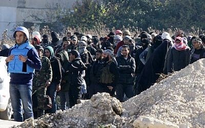 Syrian civilians and rebel forces wait for the buses as they began evacuating the last opposition-held district of Waer in the central city of Homs, under a deal with the Syrian regime, December 9, 2015. (AFP/Louai Beshara)
