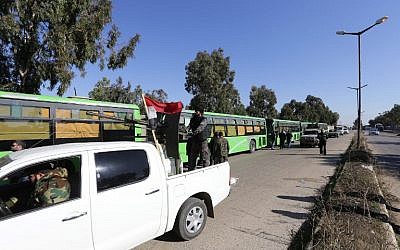 Syrian government forces escort buses carrying Syrian rebel fighters as hundreds of civilians and rebel forces began evacuating the last opposition-held district of Waer in the central city of Homs, under a deal with the Syrian regime, December 9, 2015. (Photo by AFP Photo/Louai Beshara)