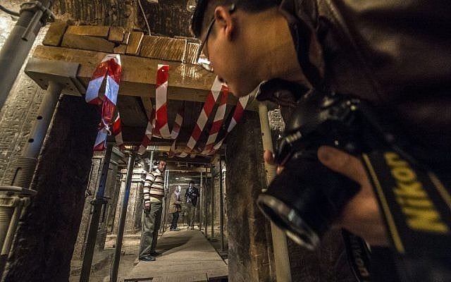 A photographer looks through the entrance of the tomb of Maia, the wet-nurse of legendary Egyptian boy king Tutankhamun, in Saqqara, Egypt, on December 20, 2015. (AFP/KHALED DESOUKI)