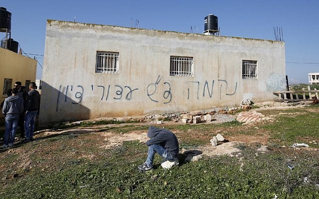 Palestinians gather next to a house sprayed with graffiti reading in Hebrew: 'revenge' and 'hello from the prisoners of Zion,' in the West Bank village of Beitillu on December 22, 2015.(AFP PHOTO/ABBAS MOMANI) Palestinians gather next to a house sprayed with graffiti reading in Hebrew: 'revenge' and 'hello from the prisoners of Zion,' in the West Bank village of Beitillu on December 22, 2015.(AFP PHOTO/ABBAS MOMANI)
