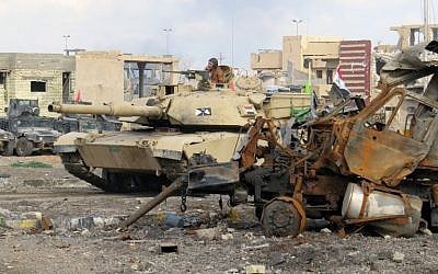 Iraqi counterterrorism forces drive a tank past rubble south of the Anbar province's capital of Ramadi, on December 24, 2015. (AFP/STR)