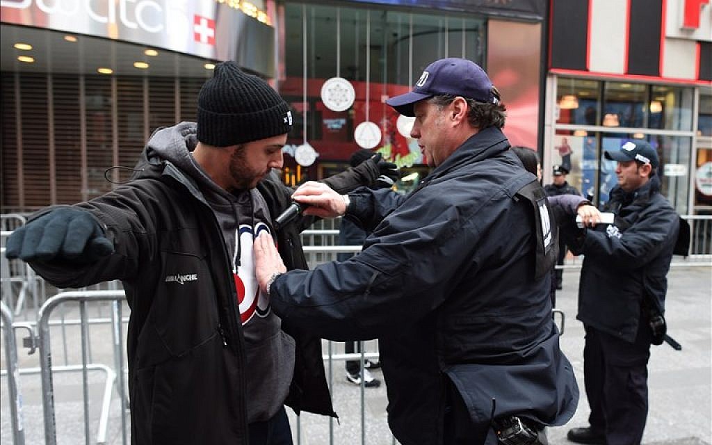 A New York City police officer inspects a reveler joining the crowd in Times Square on December 31, 2015 in New York. (AFP PHOTO/DON EMMERT)