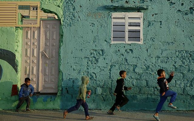 Palestinian boys running by a painted house in the Shati refugee camp in Gaza City on December 19, 2015. (AP Photo/Hatem Moussa)