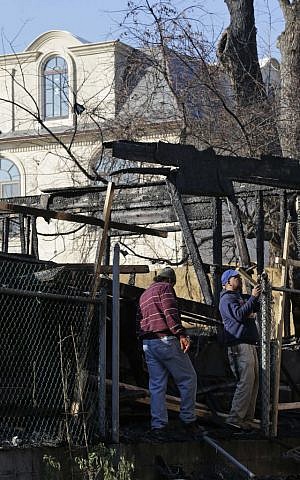 A large single family home rises above men working in the remains of a construction site that was destroyed by arson in the Forest Hills section of Queens in New York, Monday, Dec. 7, 2015. Over the past six weeks, an arsonist has torched six buildings in the same tight-knit section of eastern Queens, police say. Police aren't sure whether the victims are being targeted for their religion, their architectural taste, or for no reason at all. (AP Photo/Seth Wenig)