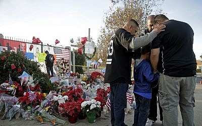 Mourners comfort each other at a makeshift memorial site honoring Wednesday's shooting victims Monday, Dec. 7, 2015 in San Bernardino, Calif. Thousands of employees of San Bernardino County are preparing to return to work Monday, five days after a county restaurant inspector and his wife opened fire on a gathering of his co-workers, killing 14 people and wounding 21. (AP Photo/Jae C. Hong)