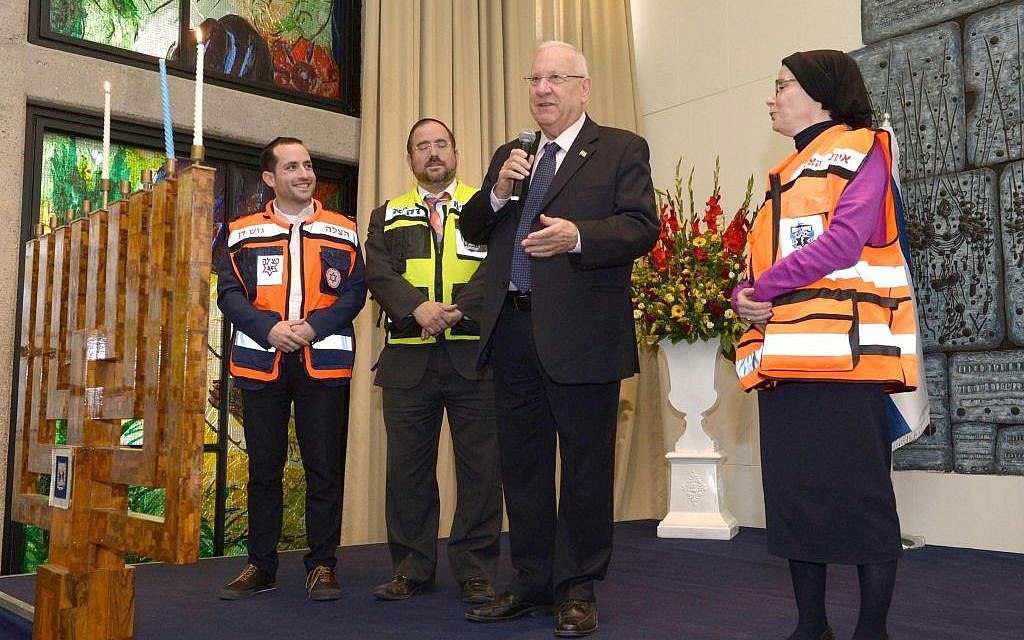 President Reuven Rivlin lighting the second candle on Hanukkah together with 100 representatives of rescue organizations, on December 7, 2015. (Mark Neyman/GPO)