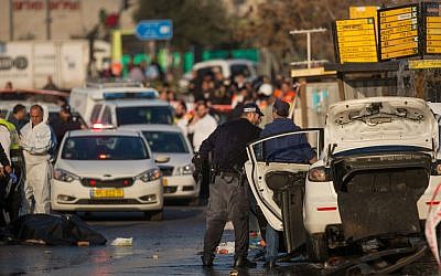 Israeli security personnel at the scene where a Palestinian driver rammed his car into a bus stop injuring about 13 people who were waiting there, on Herzl Boulevard at the entrance to the city of Jerusalem, on December 14, 2015. The body of the attacker can be seen covered by a sheet on the left. (Yonatan Sindel/Flash90)
