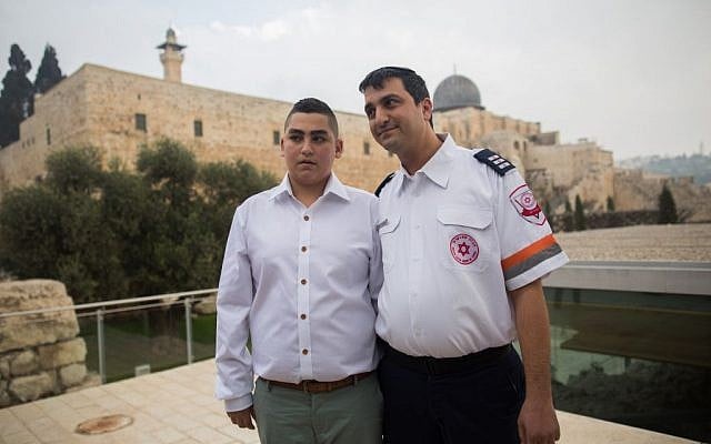 13-year-old Naor Shalev Ben-Ezra poses for a picture with the paramedic who saved his life as he celebrates his bar-mitzvah with family and friends at the Western Wall in Jerusalem's Old City on December 17, 2015. (Yonatan Sindel/Flash90)