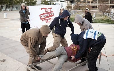 Right-wing Jewish activists protest against alleged torture by the Shin Bet security service by reenacting the supposed techniques in Habima square in Tel Aviv on December 23, 2015.(Tomer Neuberg/Flash90)