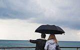 A couple holding an umbrella on a rainy day look out over the sea, at the Tel Aviv port. (December 18, 2015. (Esther Rubyan/FLASH90)