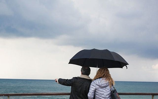A couple holding an umbrella on a rainy day look out over the sea, at the Tel Aviv port. (December 18, 2015. (Esther Rubyan/FLASH90) A couple holding an umbrella on a rainy day look out over the sea, at the Tel Aviv port. (December 18, 2015. (Esther Rubyan/FLASH90)
