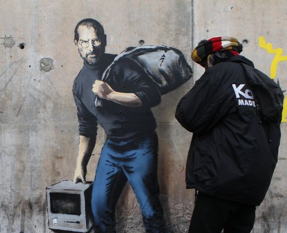 A painting by English graffiti artist Banksy is seen at the entrance of the Calais refugee camp in France, Saturday, Dec. 12, 2015. (AP Photo/Michel Spingler)