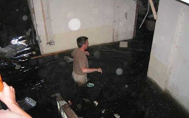Former Chief Warrant Officer 4 Richard Gonzales wades through waist-deep sewage in the basement of the Mukhabarat, Saddam Hussein's secret police headquarters, on May 6, 2003, Baghdad, Iraq. (Courtesy: Richard Gonzales)