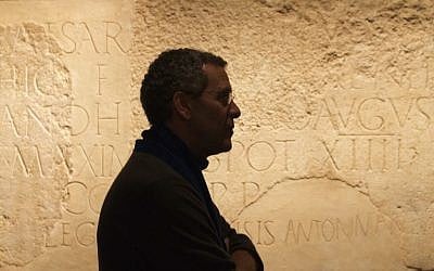 Curator David Mevorach and a monumental inscription dedicated to Roman Emperor Hadrian at an Israel Museum exhibit opening December 22, 2015. (Moti Tufeld)