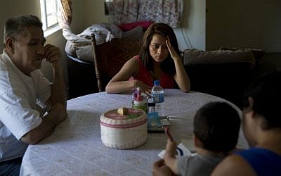 In this June 8, 2015, file photo, 18-year-old Dunia Bueso, center, and her relative, Augustin Vargas, left, look at Bueso's 1-year-old son, Joshua Tinoco, foreground, sitting on the lap of Martina Perez, at their home in Los Angeles. At a brief hearing, a government lawyer told the teenage mother that her son is an immigration enforcement priority for the United States and should be sent back to his native Honduras even though she is being allowed to stay and seek a green card. (AP Photo/Jae C. Hong, File)