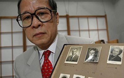 FILE - In this July 26, 2010 file photo, Akira Kitade holds a photo album that belonged to a former colleague of his at the Japan Tourist Bureau, Tatsuo Osako, during an interview in Tokyo. The page displayed holds seven photos given to Osako by people whom Osako helped escape from Europe in the early days of World War II. (Shizuo Kambayashi/AP)