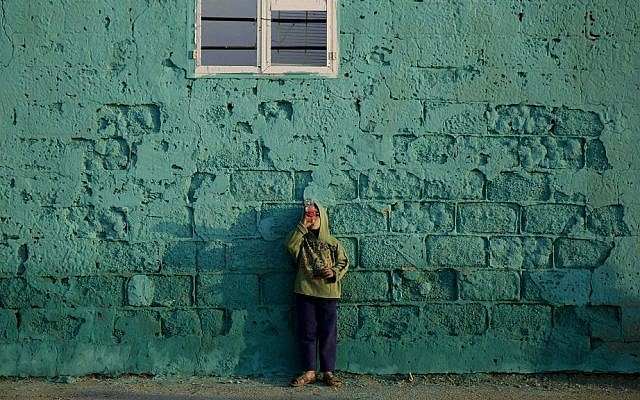 In this Saturday Dec. 19, 2015 photo, a Palestinian boy drinks a soda by the painted house wall in the Shati refugee camp in Gaza City. (AP Photo/Hatem Moussa)